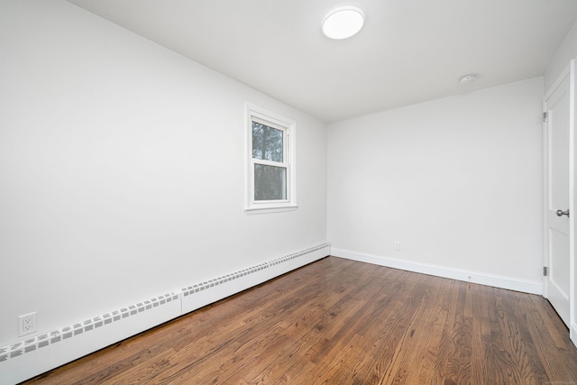 unfurnished room featuring hardwood / wood-style floors and a baseboard heating unit