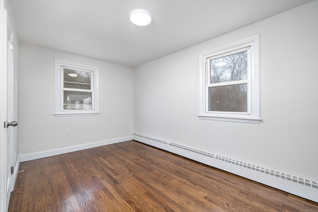 empty room with hardwood / wood-style flooring, baseboard heating, and plenty of natural light