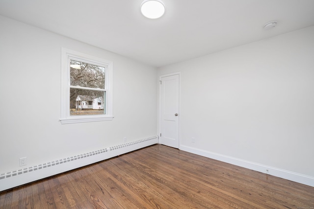 spare room featuring baseboard heating and wood-type flooring