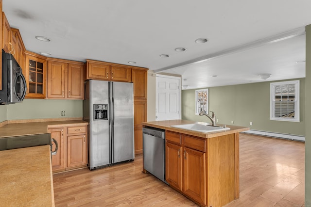 kitchen featuring light hardwood / wood-style flooring, stainless steel appliances, an island with sink, sink, and a baseboard heating unit