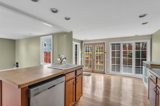 kitchen with light hardwood / wood-style floors, a kitchen island with sink, stainless steel dishwasher, and sink