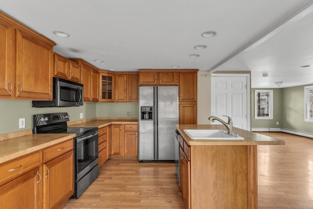 kitchen with sink, stainless steel appliances, an island with sink, and light hardwood / wood-style floors