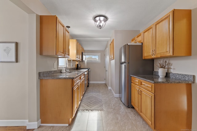 kitchen with dark stone countertops, sink, light tile patterned floors, and appliances with stainless steel finishes