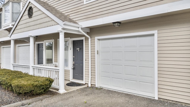 doorway to property featuring covered porch and a garage