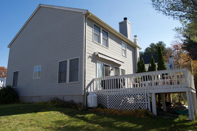 back of property with a wooden deck and a yard