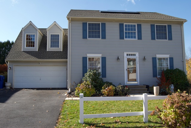 colonial home featuring a front yard and a garage