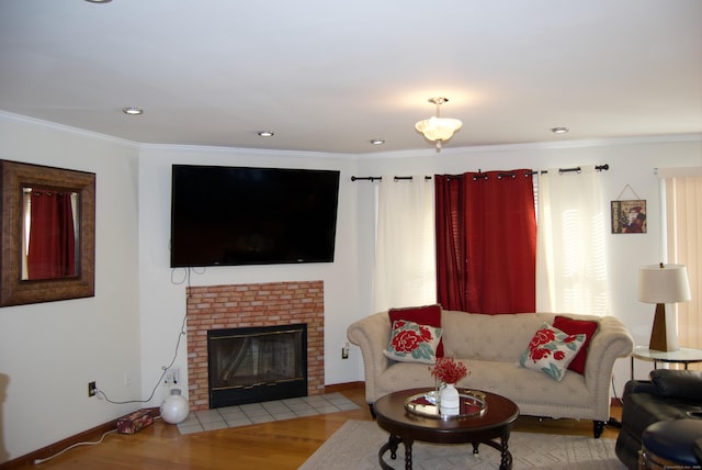 living room featuring a brick fireplace, ornamental molding, and light hardwood / wood-style floors