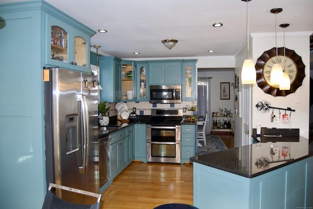 kitchen featuring pendant lighting, stainless steel appliances, kitchen peninsula, light wood-type flooring, and blue cabinets