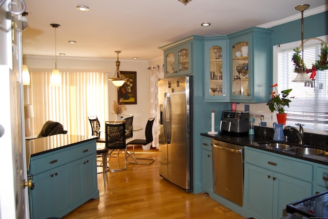 kitchen featuring pendant lighting, sink, crown molding, stainless steel appliances, and blue cabinets