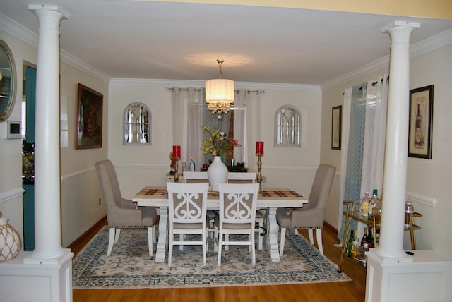 dining room featuring crown molding, light wood-type flooring, an inviting chandelier, and decorative columns