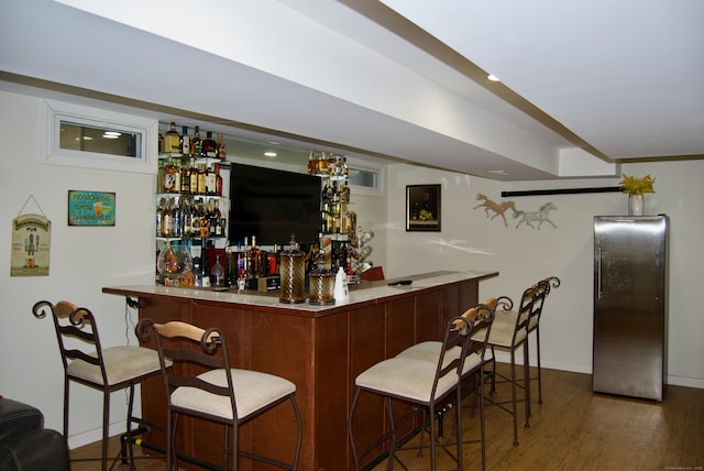 bar with dark wood-type flooring and stainless steel refrigerator