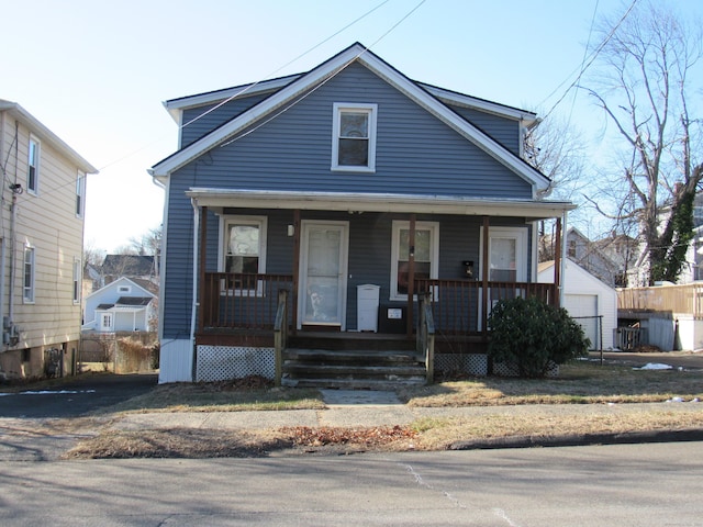 bungalow-style house with a garage, covered porch, and an outbuilding