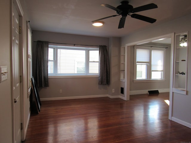 unfurnished room with ceiling fan and dark wood-type flooring