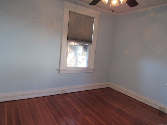 empty room with ceiling fan, dark wood-type flooring, and crown molding