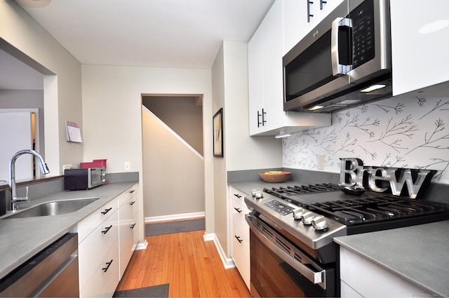 kitchen with white cabinetry, stainless steel appliances, light hardwood / wood-style floors, sink, and decorative backsplash