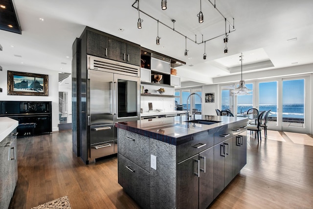 kitchen featuring sink, stainless steel built in fridge, a large island, a water view, and a tray ceiling