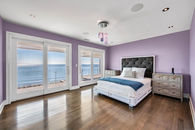 bedroom with access to outside, dark hardwood / wood-style flooring, and a water view