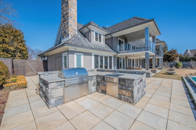 view of patio with a balcony, a grill, an outdoor kitchen, and sink