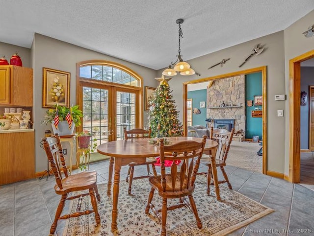 85 Salem Rd, East Haddam, CT 06415 - dining room with a textured ceiling, a stone fireplace, light tile patterned floors, french doors, and a chandelier