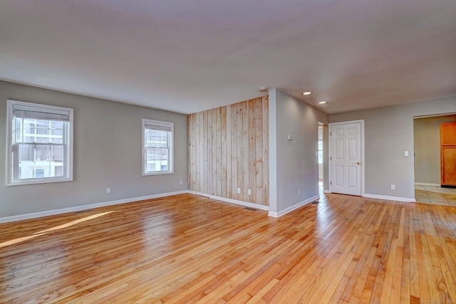 empty room with light wood-type flooring and wooden walls