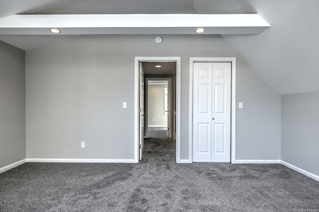 additional living space with dark colored carpet and vaulted ceiling