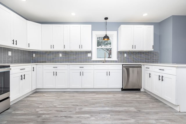 kitchen with hanging light fixtures, light wood-type flooring, stainless steel appliances, and white cabinetry