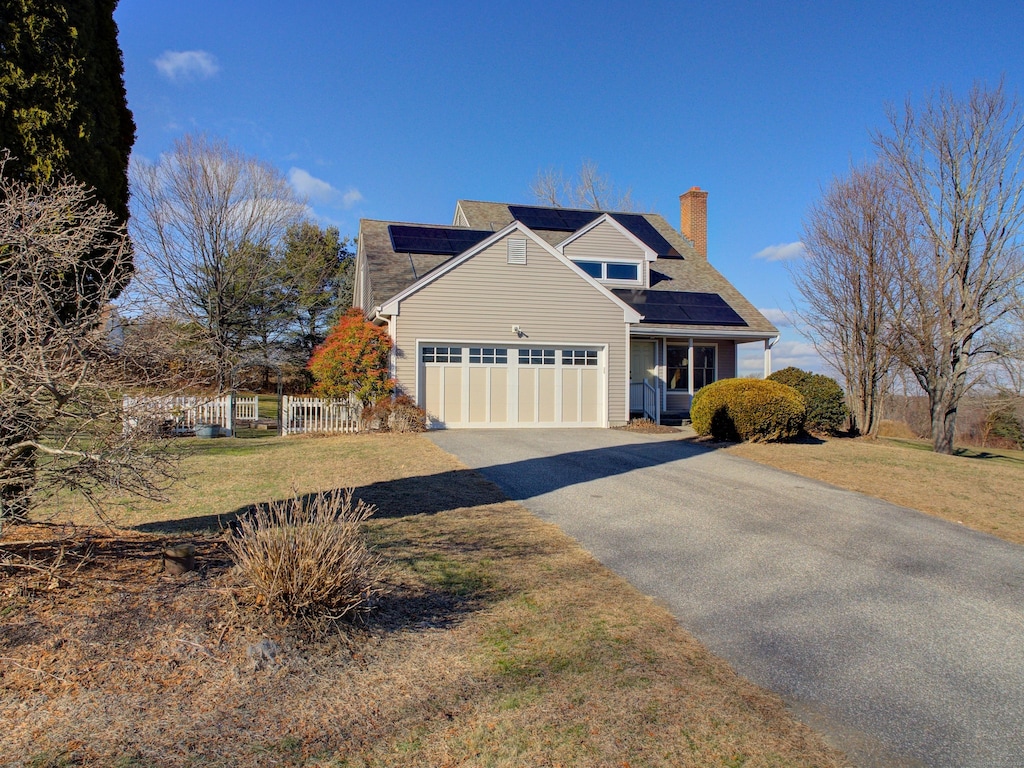 view of front of home featuring solar panels, a front yard, and a garage