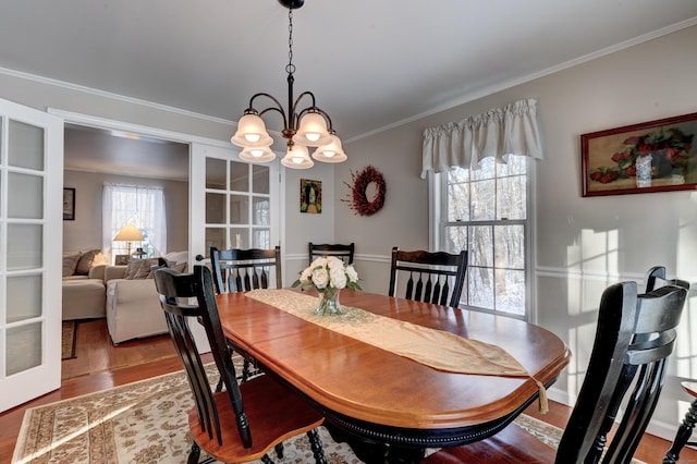 dining area with hardwood / wood-style flooring, crown molding, an inviting chandelier, and french doors