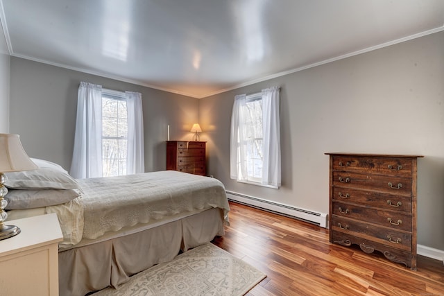 bedroom with a baseboard radiator, ornamental molding, and light hardwood / wood-style flooring