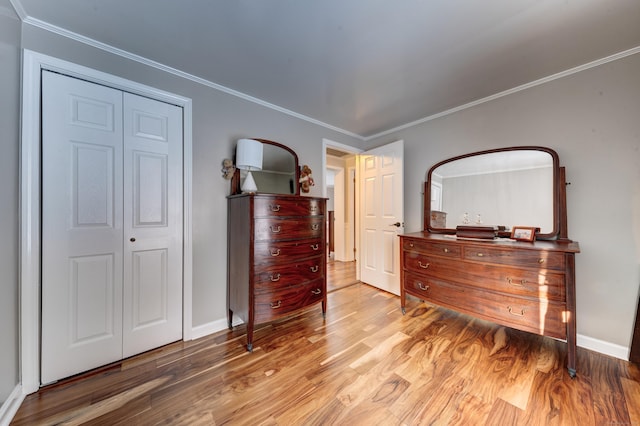 bedroom with light hardwood / wood-style flooring, ornamental molding, and a closet