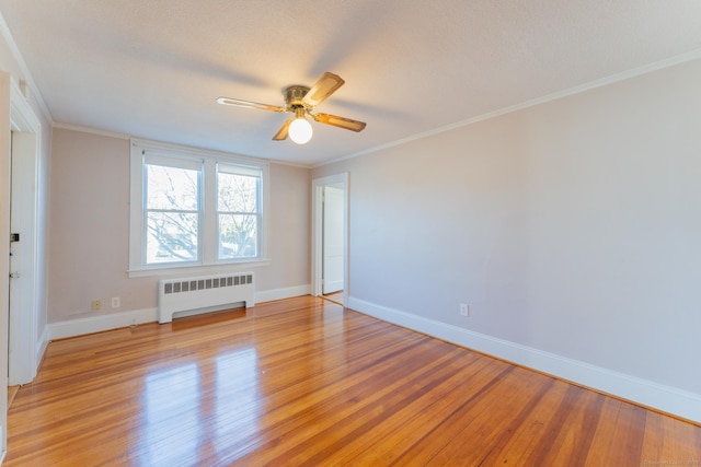 spare room with radiator, ornamental molding, ceiling fan, and light hardwood / wood-style flooring