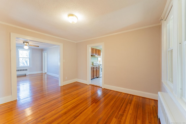 empty room featuring crown molding, hardwood / wood-style flooring, and radiator