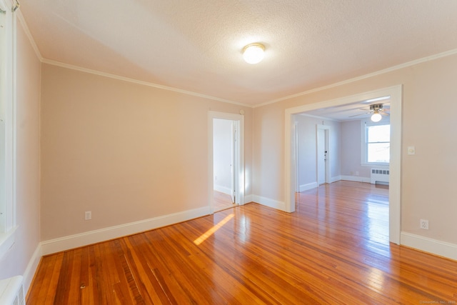 unfurnished room featuring a textured ceiling, radiator heating unit, ornamental molding, and hardwood / wood-style flooring