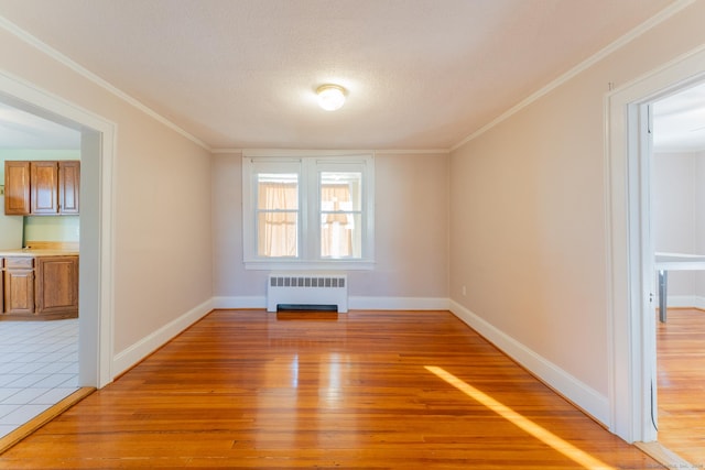 empty room featuring wood-type flooring, radiator heating unit, a textured ceiling, and crown molding