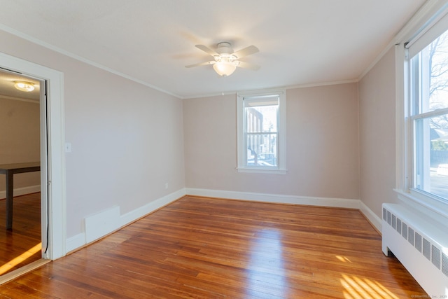 spare room with ceiling fan, wood-type flooring, ornamental molding, and radiator heating unit