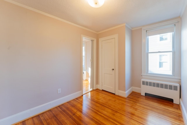 unfurnished bedroom featuring radiator, ornamental molding, and light hardwood / wood-style floors