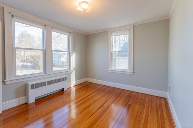 unfurnished room featuring crown molding, radiator heating unit, and light hardwood / wood-style flooring