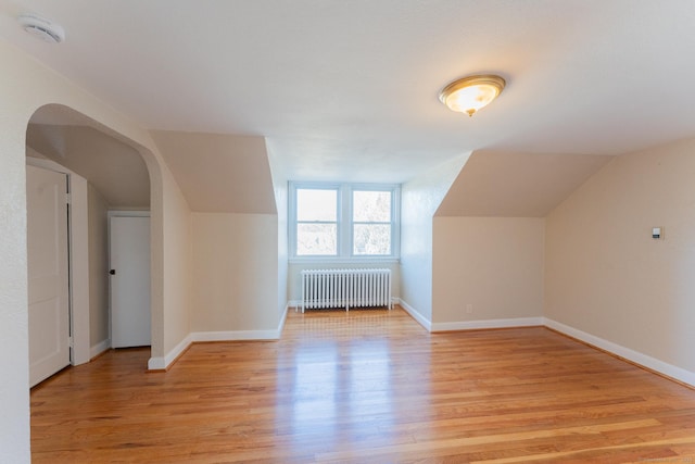 additional living space with light hardwood / wood-style flooring, radiator heating unit, and lofted ceiling