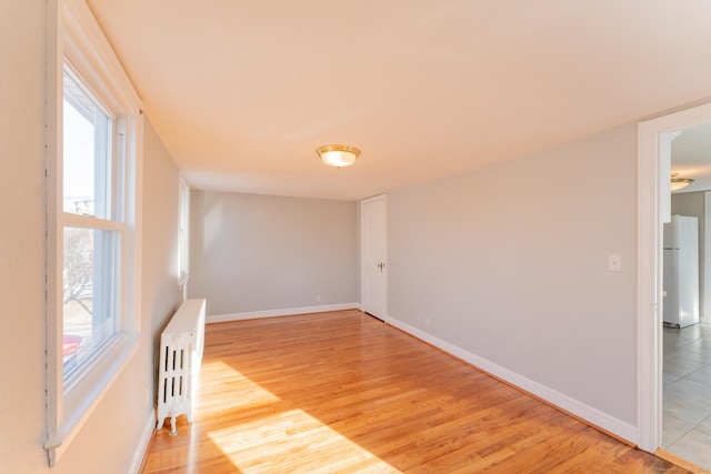 empty room with light wood-type flooring and radiator heating unit