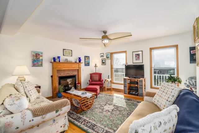 living room featuring a brick fireplace, hardwood / wood-style floors, and ceiling fan