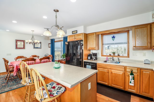 kitchen featuring black appliances, a kitchen island, sink, hanging light fixtures, and a chandelier