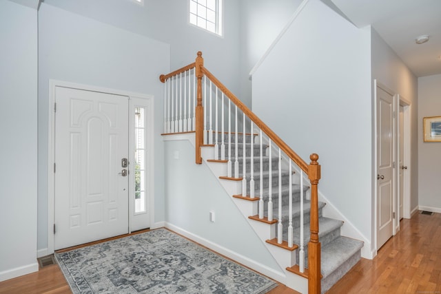 entrance foyer with a towering ceiling and light hardwood / wood-style flooring