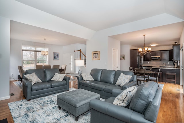 living room with an inviting chandelier, lofted ceiling, and hardwood / wood-style flooring