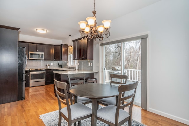 dining area featuring light wood-type flooring, an inviting chandelier, and sink