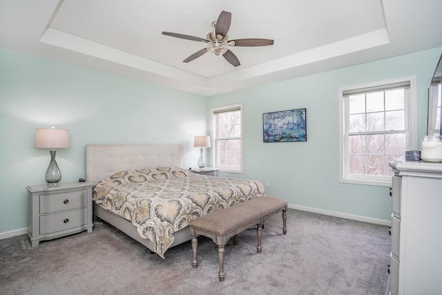 bedroom with ceiling fan, light colored carpet, and a tray ceiling