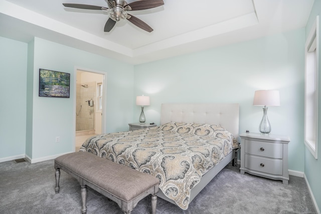 carpeted bedroom featuring a raised ceiling, ceiling fan, and connected bathroom