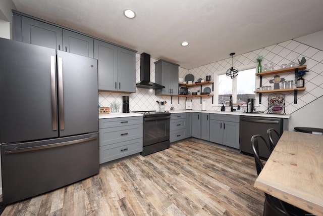 kitchen with black appliances, wall chimney exhaust hood, light hardwood / wood-style floors, backsplash, and gray cabinetry