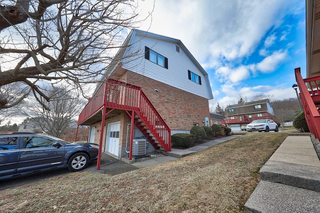 view of side of home with central air condition unit, a yard, and a garage