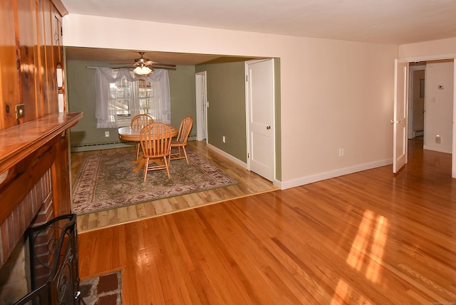 dining space featuring baseboard heating, ceiling fan, and light wood-type flooring