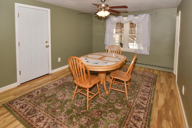 dining space featuring ceiling fan, baseboard heating, and hardwood / wood-style flooring